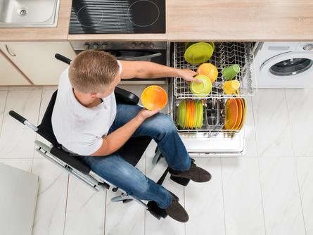 Man in a wheelchair loading a dishwasher